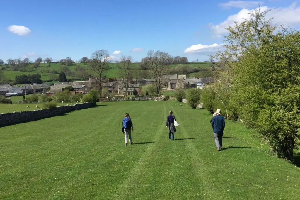People walking across a field towards the village of GreatA sby