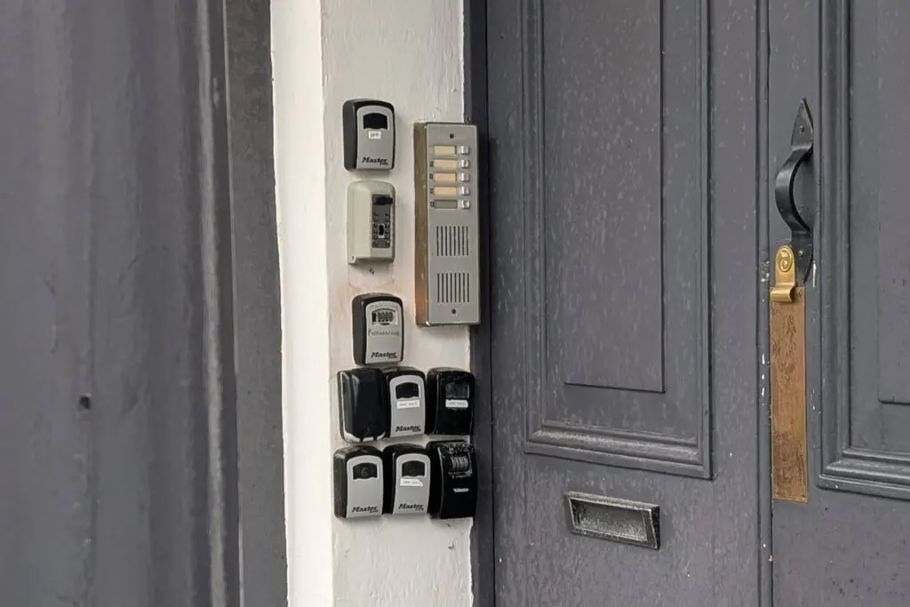 Many key safes on a door showing that there are multiple holiday lets inside