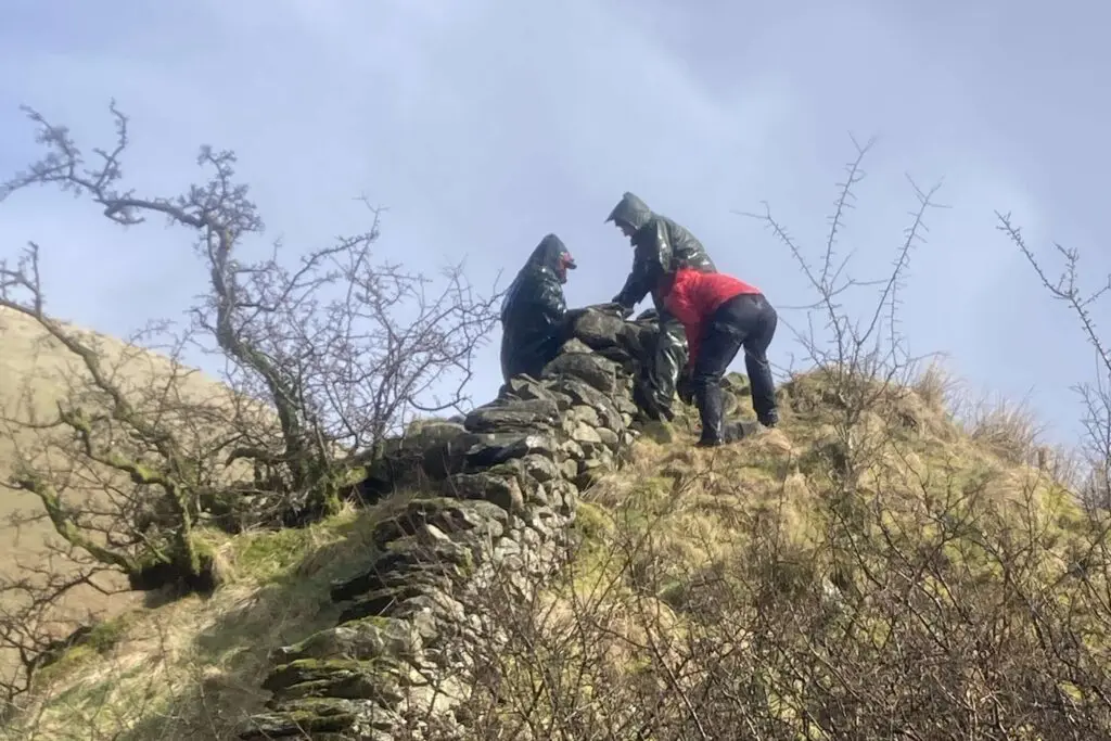 Volunteers working on a wall on top of a hill