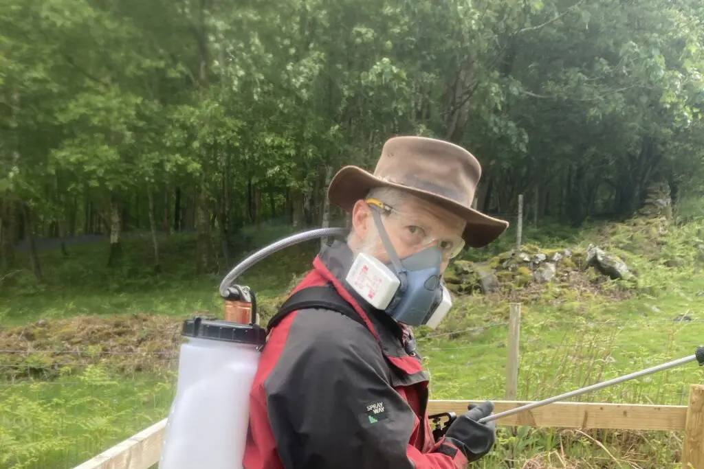 Man with a spray gun and a face mask on in Rusland woods