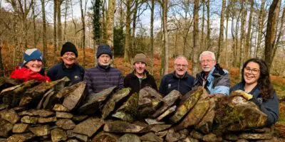 People smiling behind a dry stone wall