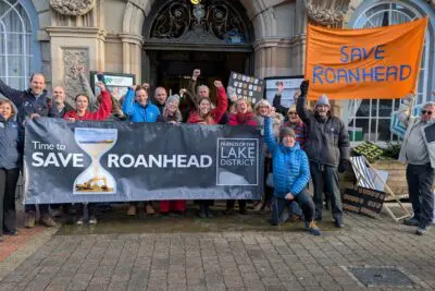 Protestors celebrate with a banner that says Save Roanhead