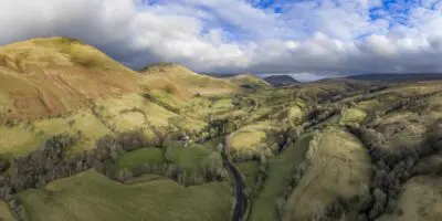 A panoramic view of hills, sky and landscape with hedges