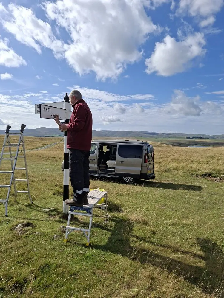 Man repainting a old signpost