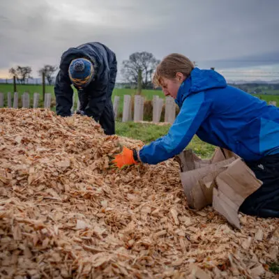 A student moving a pile of wood chippings