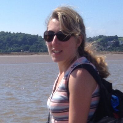 A woman in sunglasses walking across a sandy bay