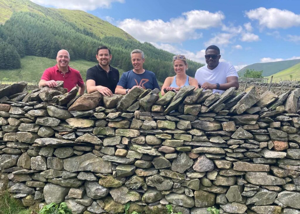 A group of people standing behind a dry stone wall