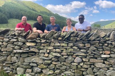 A group of people standing behind a dry stone wall