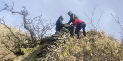 Volunteers working on a wall on top of a hill
