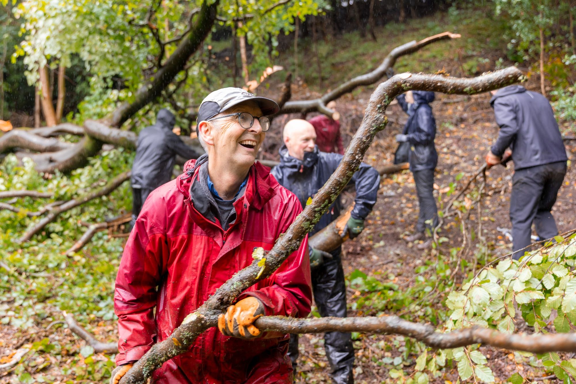 Volunteer carrying a tree branch and smiling