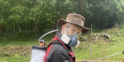 Man with a spray gun and a face mask on in Rusland woods